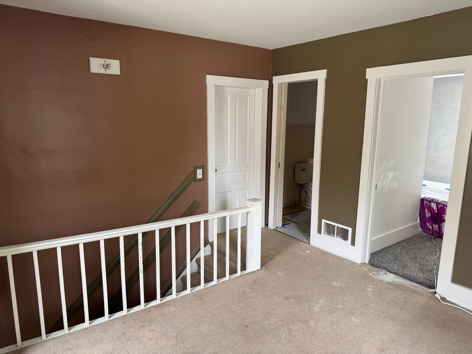 Bright stairwell landing finished in warm tan with crisp white trim and railing