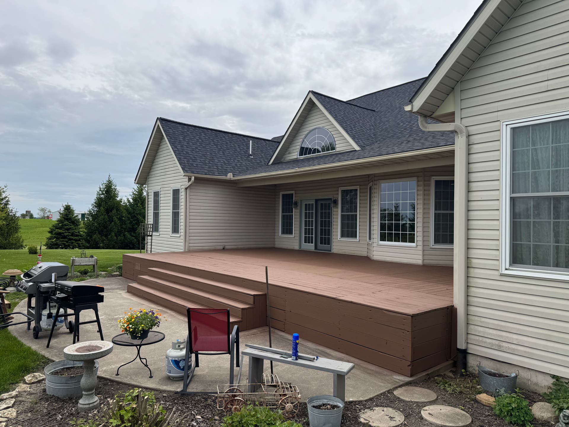 Stained wood deck across the back of a country ranch home with steps and skirting