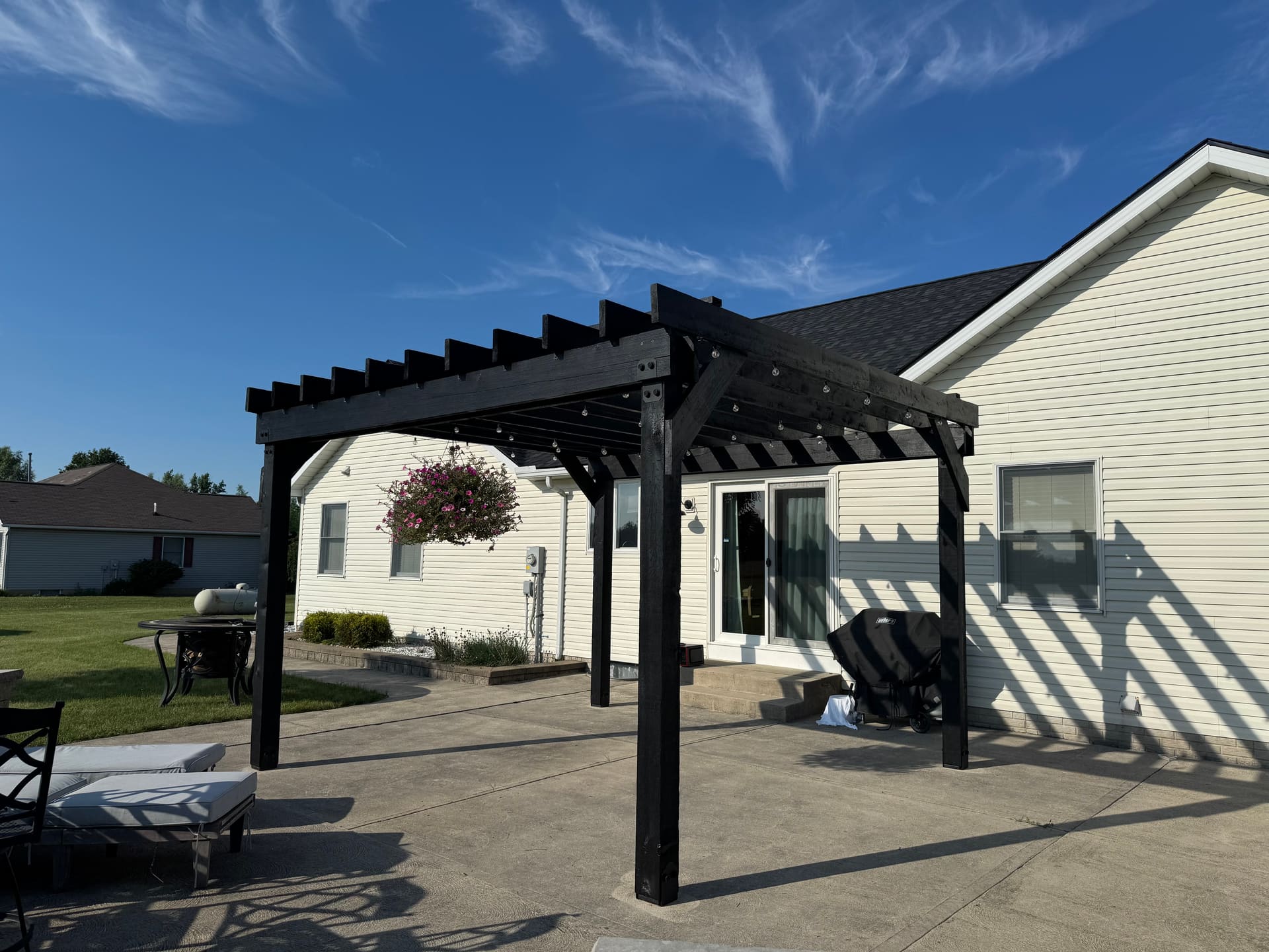 Wide angle of the black pergola, hanging flower basket adding color
