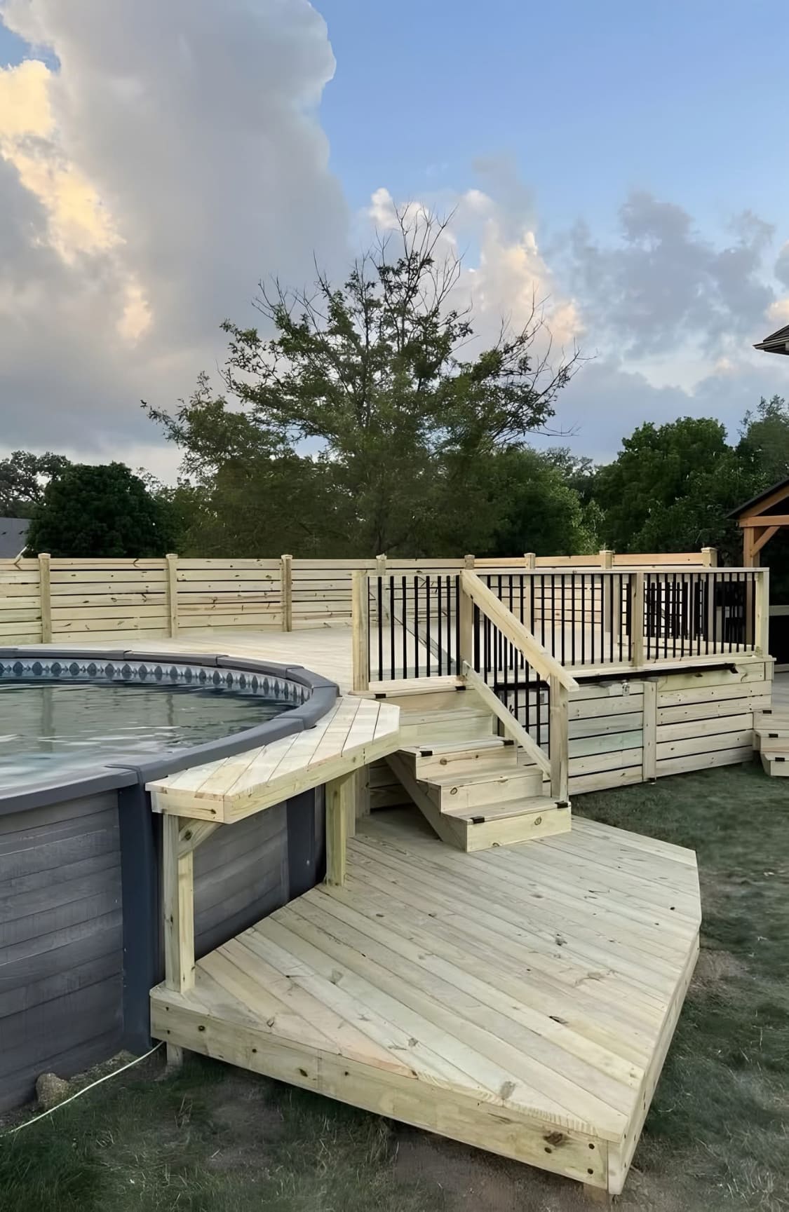 Newly built wraparound deck and steps surrounding an above-ground pool