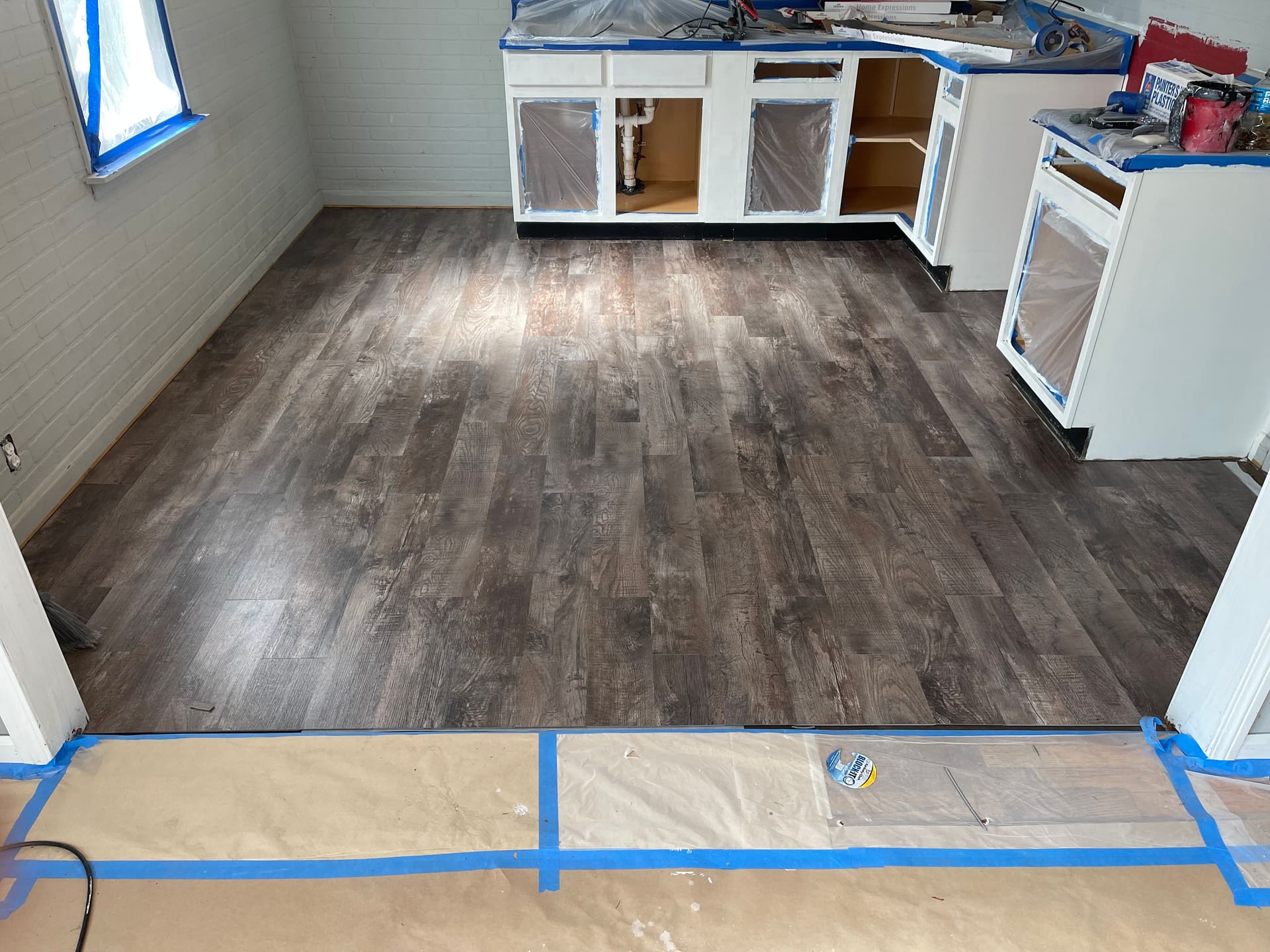 New vinyl plank flooring being installed across a kitchen during a turnover