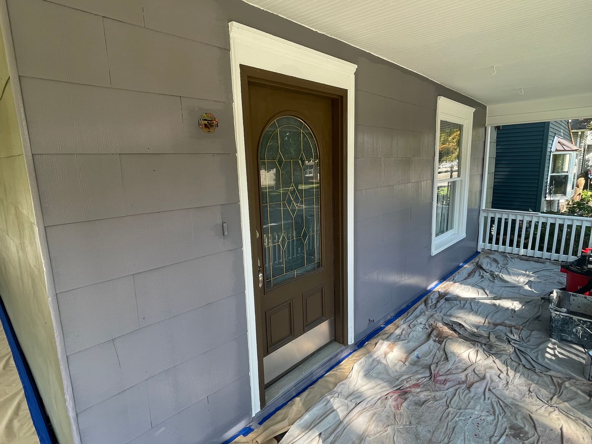 Front porch repainted in fresh white with wet paint and masking still in place